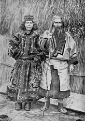 Couple Ainu devant la maison traditionnelle Ainu d